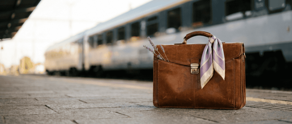 Outplacement : Mallette en cuir sur un quai de gare au matin, train flou prêt au départ