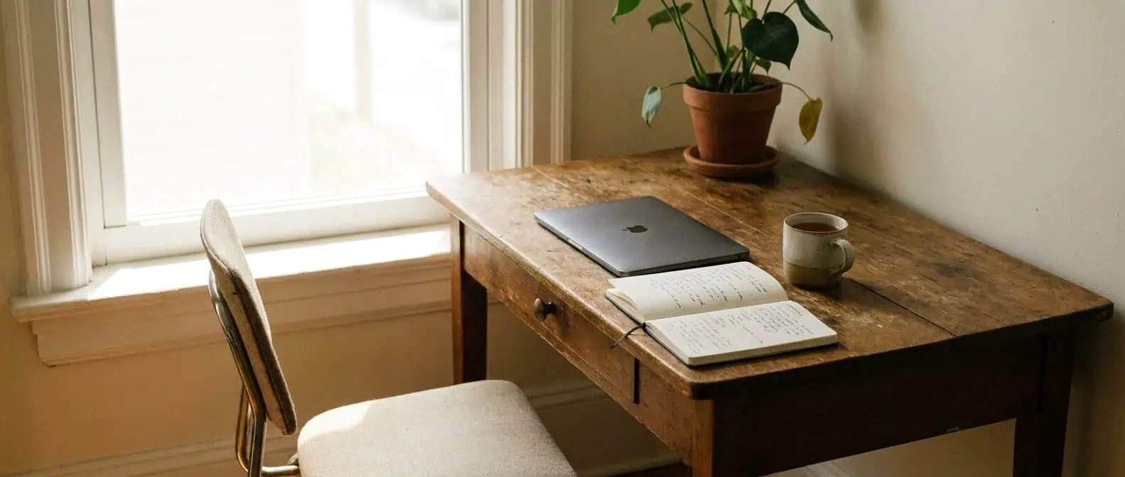 Burn out que faire : bureau en bois près d'une fenêtre lumineuse en fin de journée, chaise vide tournée vers la lumière, ordinateur portable fermé, ambiance apaisée après la tension du travail